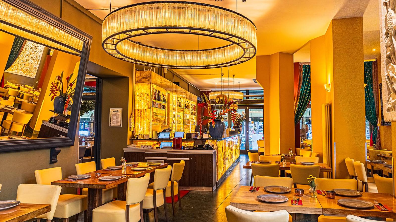 Eetzaal van AMRIT Mitte met gele muren, een grote ronde kroonluchter en gedekte tafels