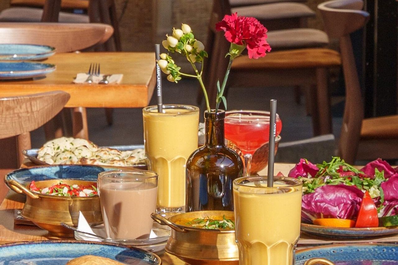 Glazen mango lassi, bloemen en Indiase gerechten op een houten tafel